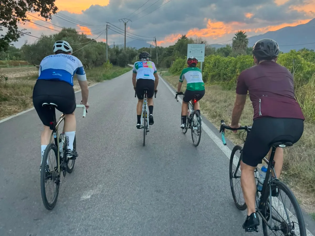 Un groupe de cyclistes vus de dos sur une route de campagne, au coucher du soleil